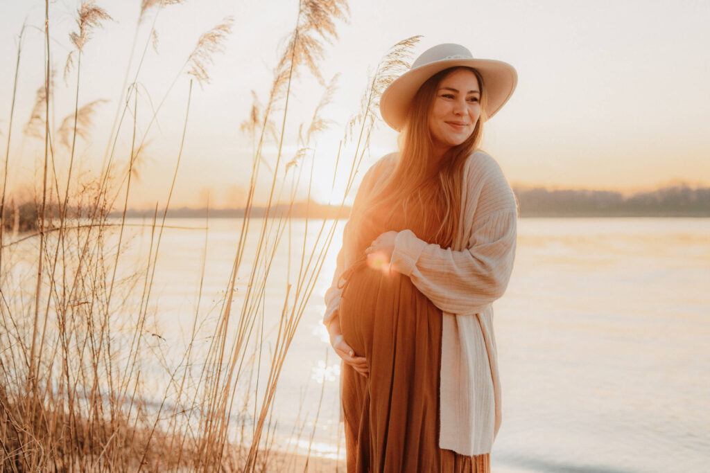babybauchshooting am strand an der elbe, schwangere hält sich den babybauch