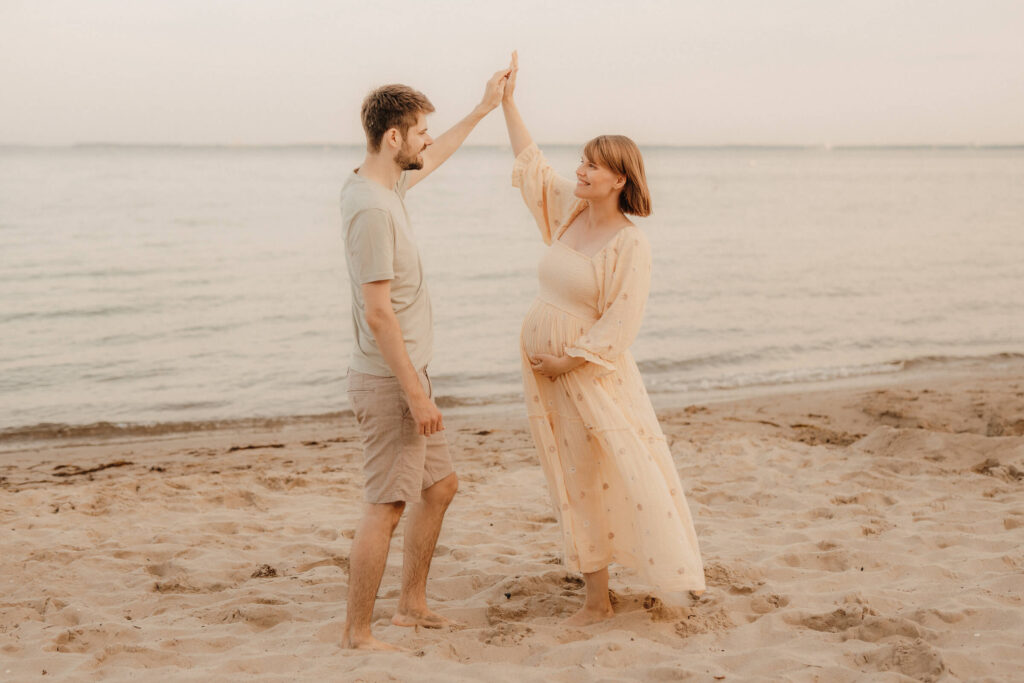 babybauchshooting, schwangere und partner tanzen und lachen