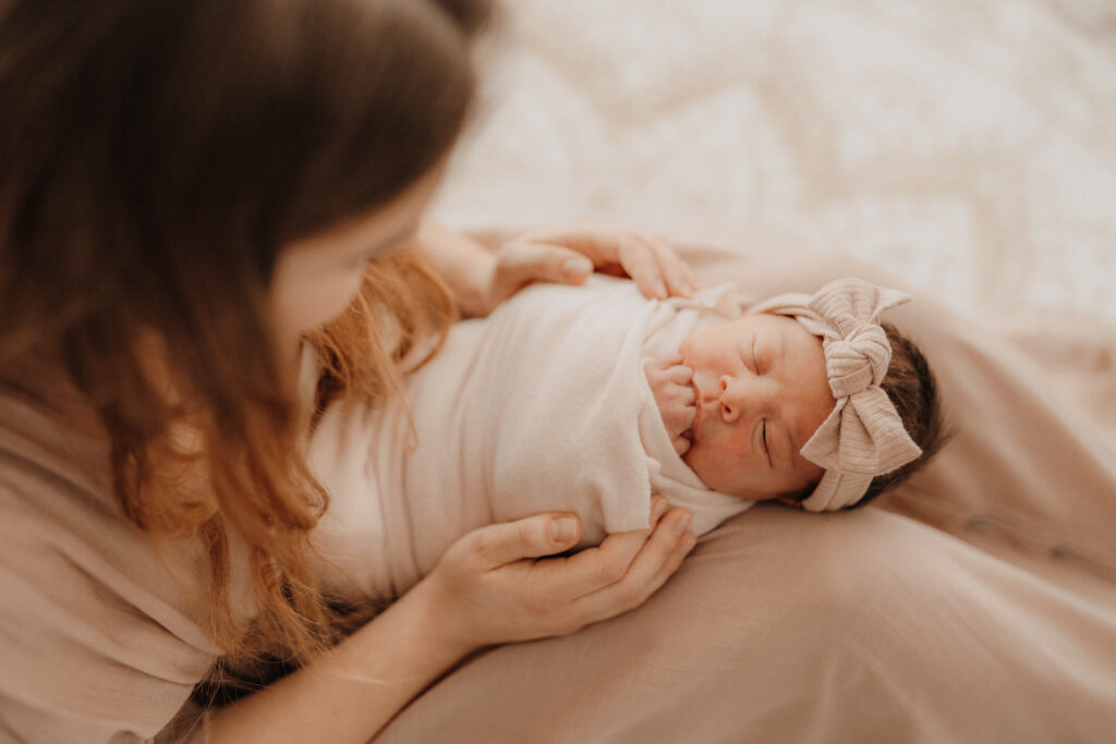 newbornshooting, baby liegt auf mamas beinen und schlaeft