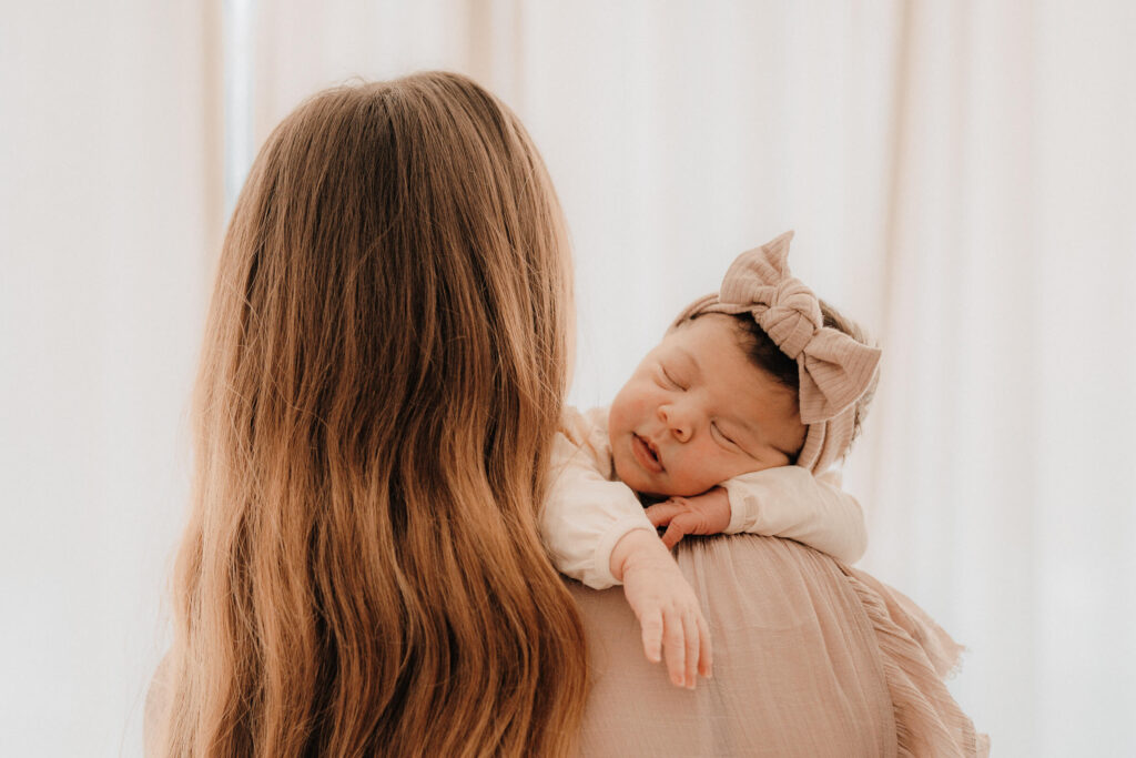 newbornshooting, baby liegt ueber mamas schulter und schlaeft