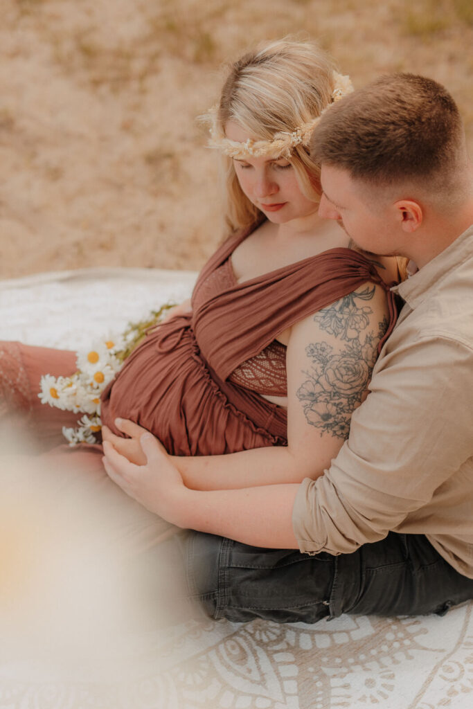 babybauchshooting boberger duenen, schwangere und partner sitzen und kuscheln