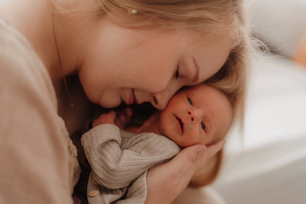 newbornshooting, baby liegt in mamas arm und sie schmiegt sich an