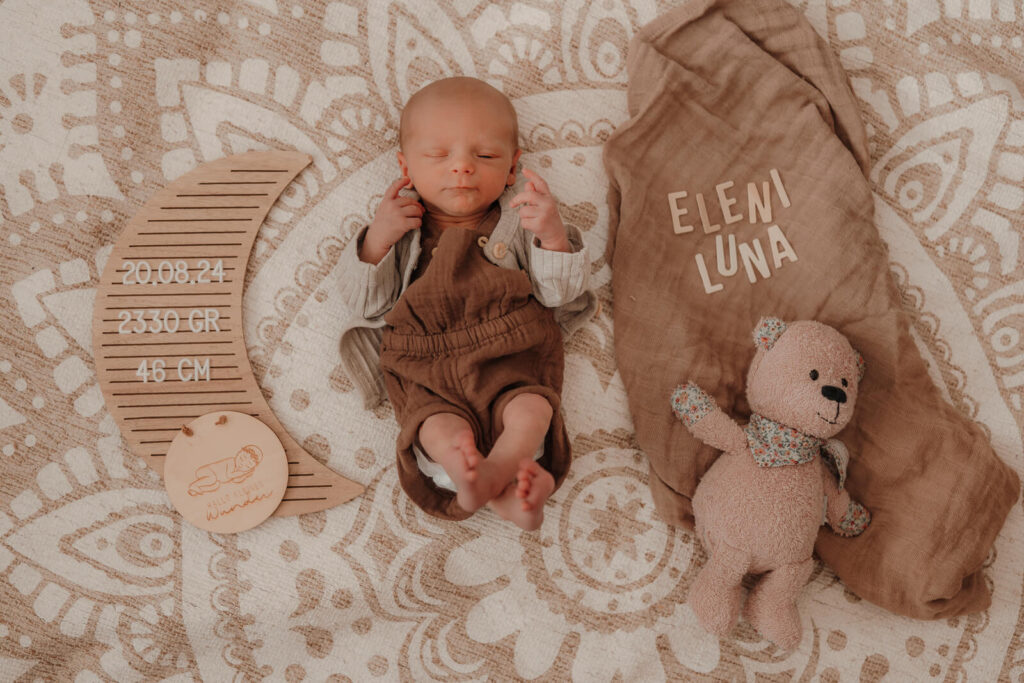 newbornshooting, baby liegt auf dem teppich mit ihrem namen in holzbuchstaben und den geburtsdaten
